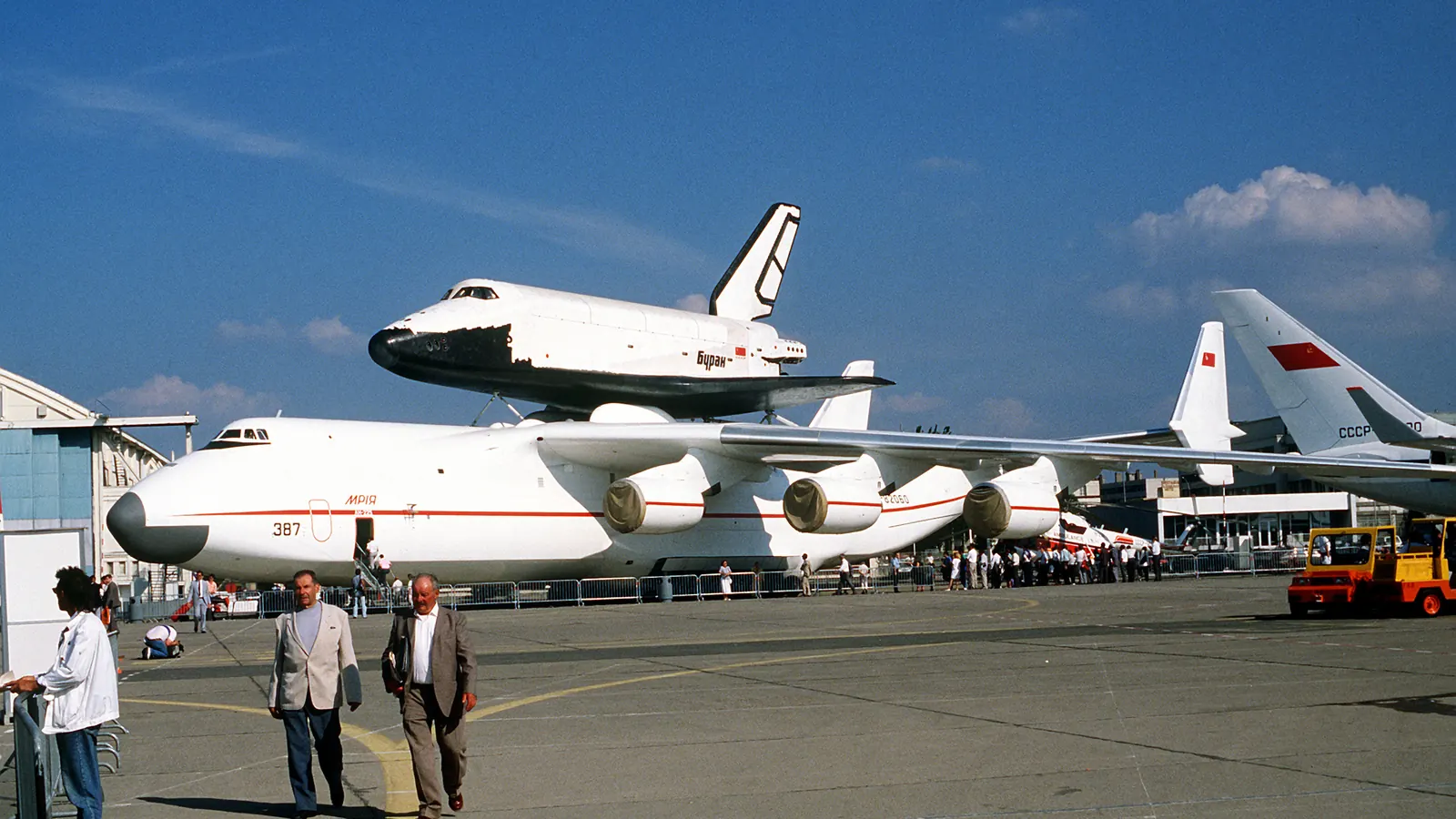 The white Buran orbiter riding on top of the giant six-engined Antonov An-225 aircraft on an airfield