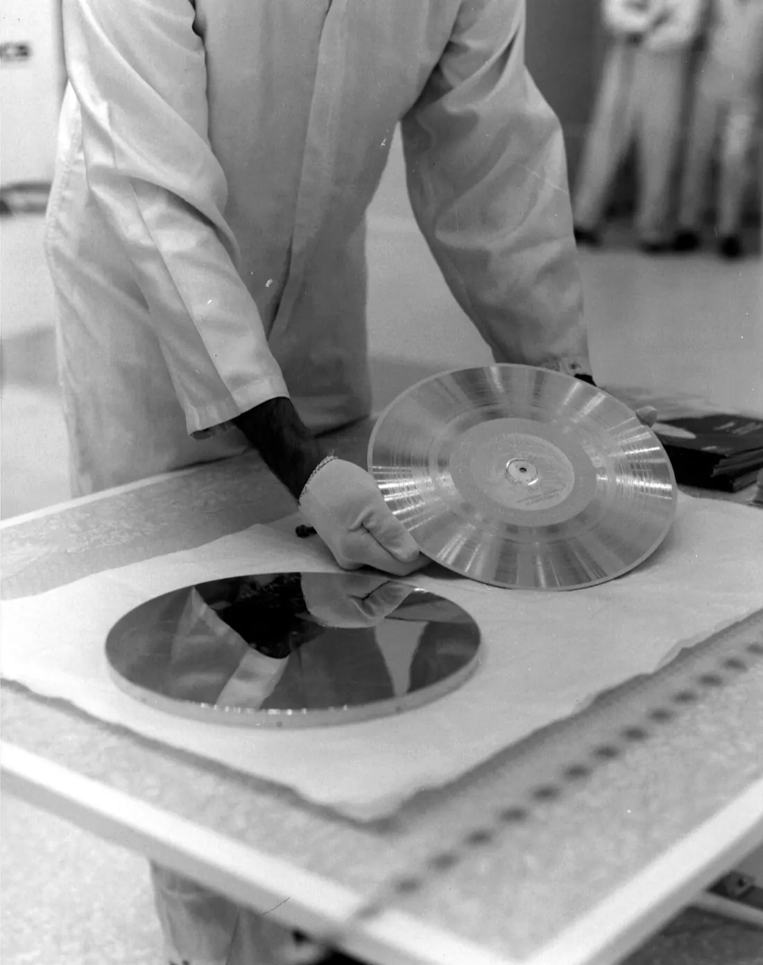 A technician in a white lab coat lays the gold record on a protective sheet